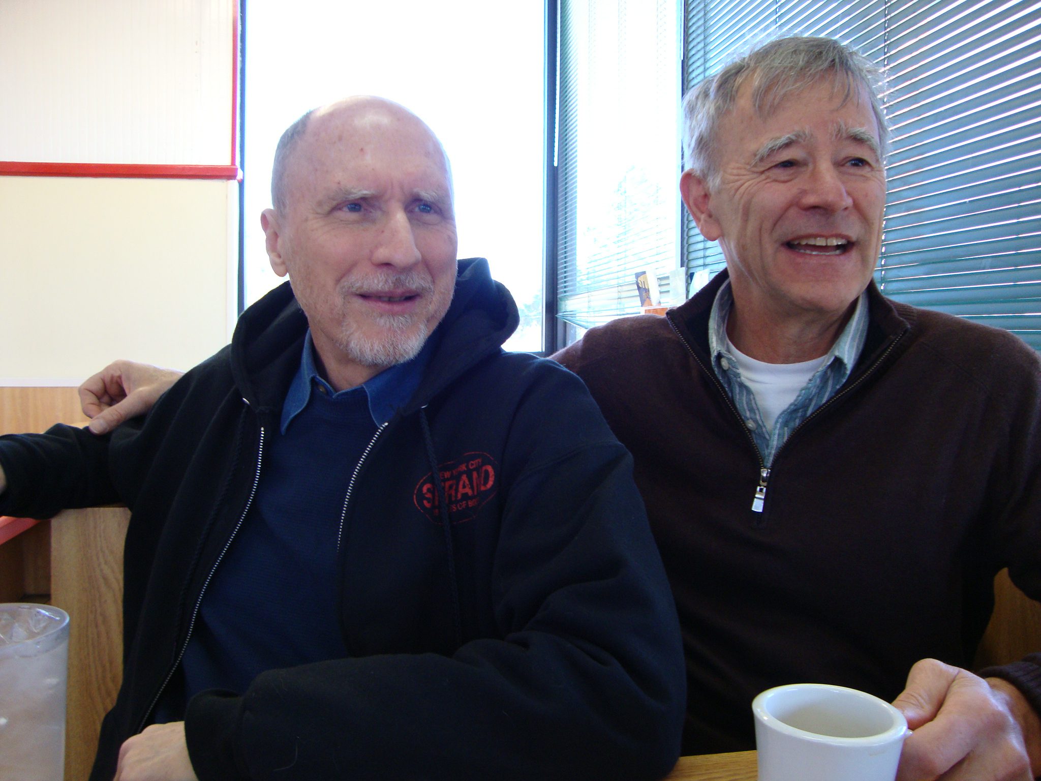 Two men sitting together, smiling warmly.