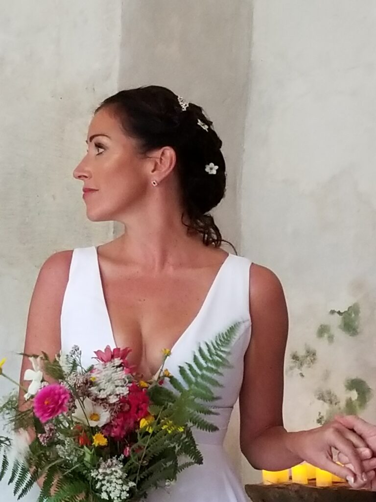Bride in white dress holding a vibrant bouquet, looking to the side.