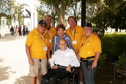 Group of five men smiling, four standing and one in a wheelchair.
