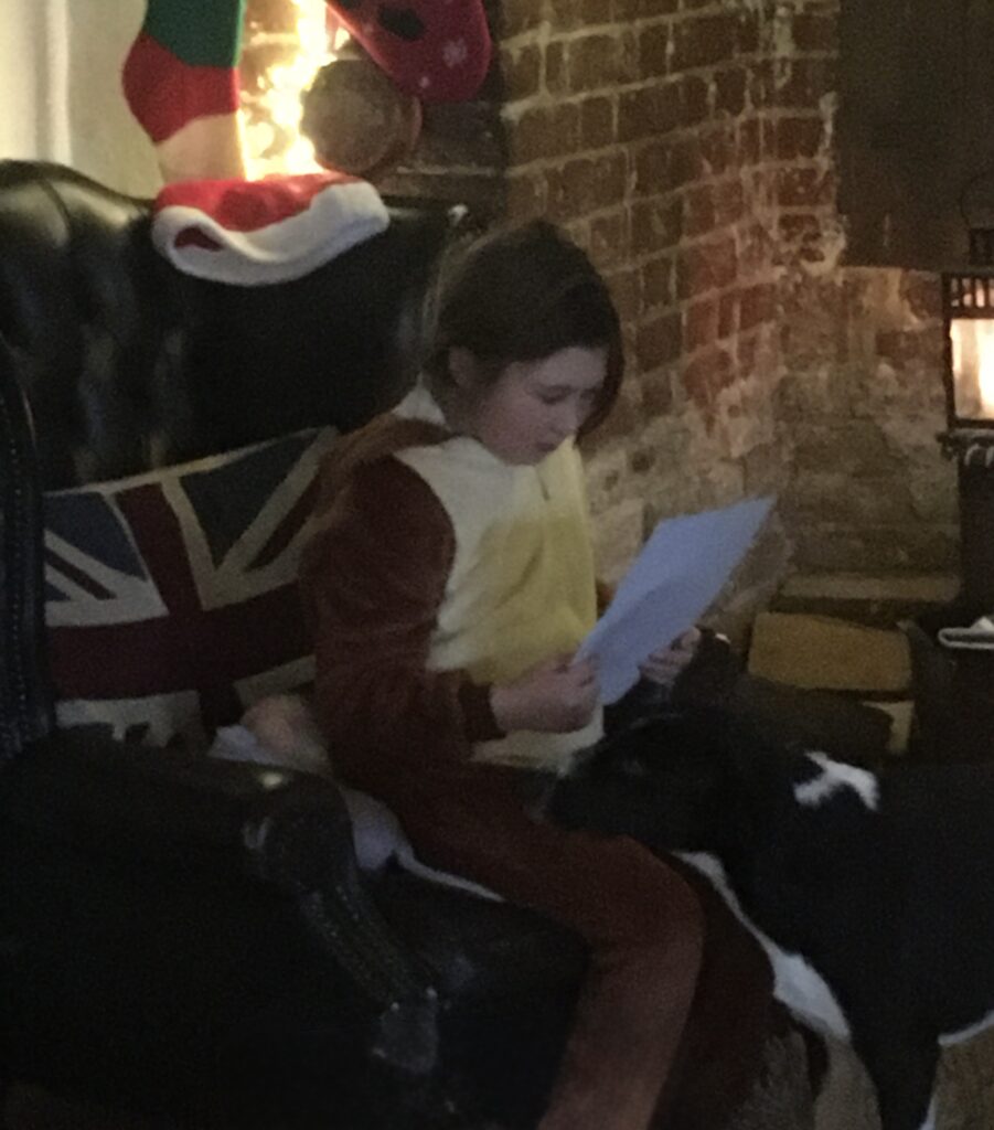 A child reading a book in a cozy room with brick walls and a Union Jack pillow.
