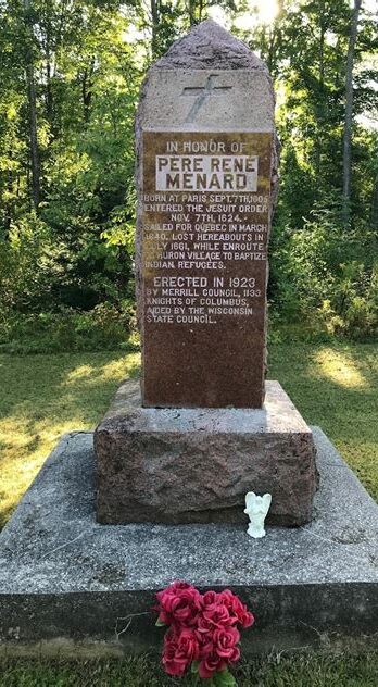 Memorial stone dedicated to fallen heroes in a peaceful green setting.