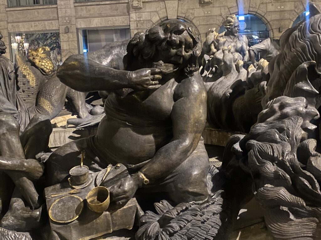 Bronze sculpture of a cherub holding a shell, surrounded by other figures.