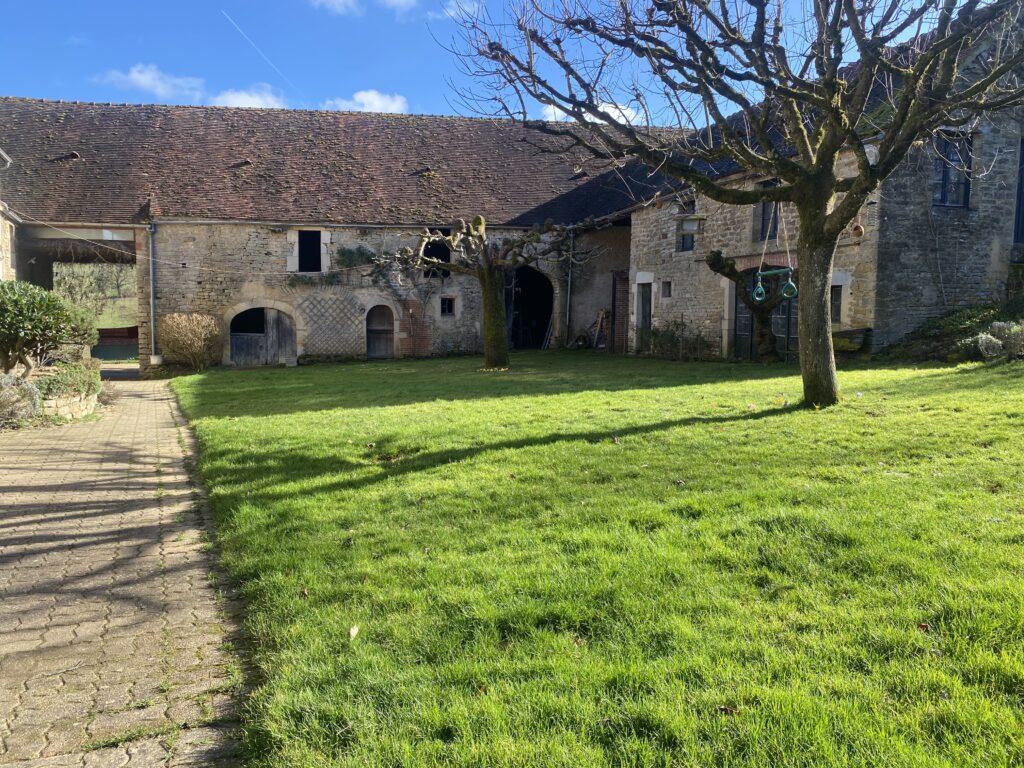 Sunny courtyard with green grass and old stone buildings.