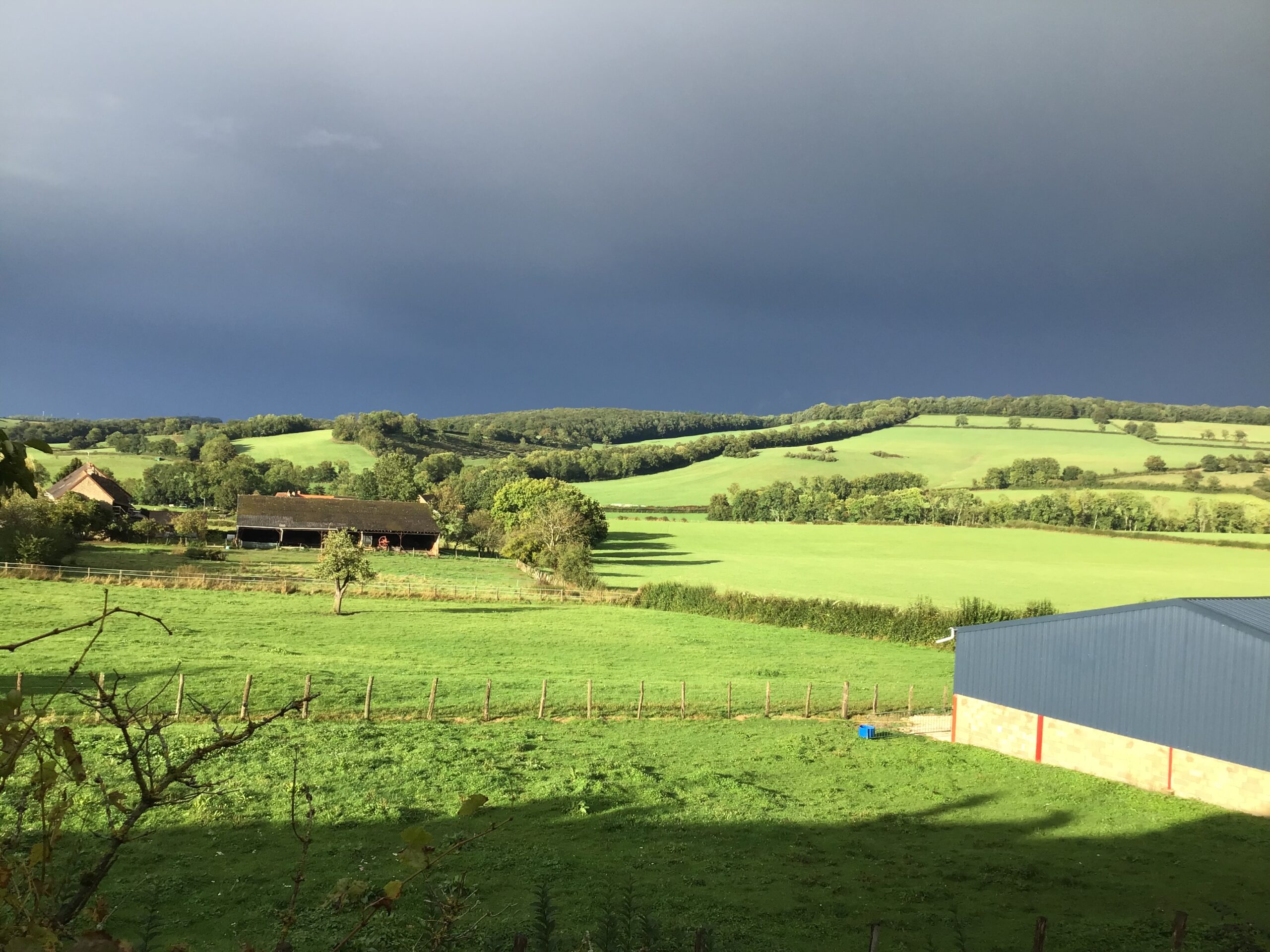 Green fields under a dark, cloudy sky.