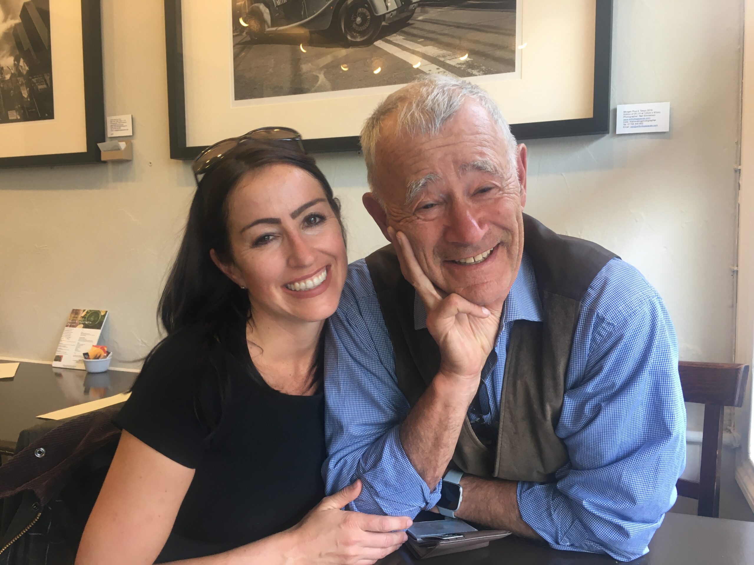 A young woman smiles warmly beside an elderly man in a cozy setting.