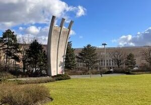 Modern concrete sculpture under a blue sky in a park.