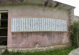 Ancient stone tablet with engraved text mounted on a weathered wall.