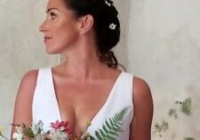 Bride in white dress holding a vibrant bouquet, looking to the side.