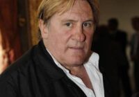 Portrait of a serious middle-aged man in a black jacket and white shirt indoors.