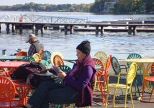 People relaxing by the lakeside with colorful chairs and a dock in the background.