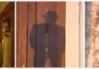 Shadow of a person wearing a hat cast on a wooden door.
