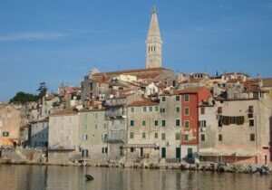 Coastal town with historic buildings and a tall bell tower.
