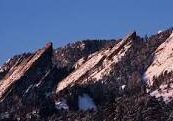 Snow-dusted rocky mountain peaks under a clear blue sky.